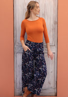 Woman pairing a beautiful wide leg, floral printed cord pants with orange stretch rayon top and boots.