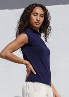 Woman wearing a navy sleeveless top against a white background