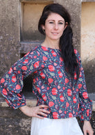 Model poses in cotton long sleeve top with bishop sleeves in red and green floral print on a navy base