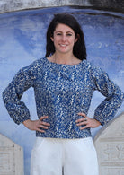 Woman with hands on waist wears top with round boat neckline and Bishop sleeves. 