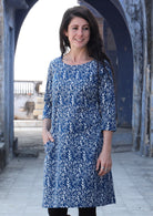 Woman standing with one hand in pocket wearing 100% cotton blue and white dress 