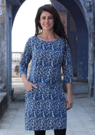 Woman standing and smiling with hand in pocket wearing 100% cotton blue and white dress 