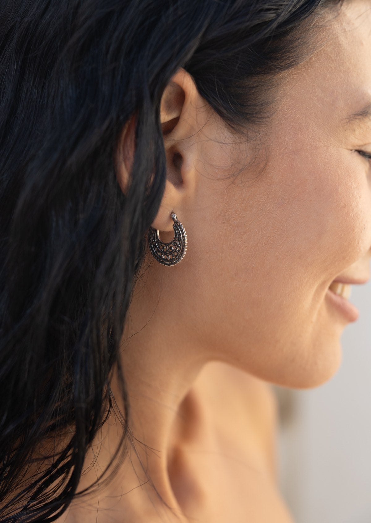 Close-up of a woman wearing a sterling silver mandala earring with intricate swirls of silver wire