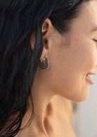 Close-up of a woman wearing a sterling silver mandala earring with intricate swirls of silver wire