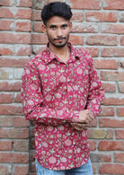 Man poses in long sleeve cotton button through shirt, adjusting the button on the cuff of one sleeve