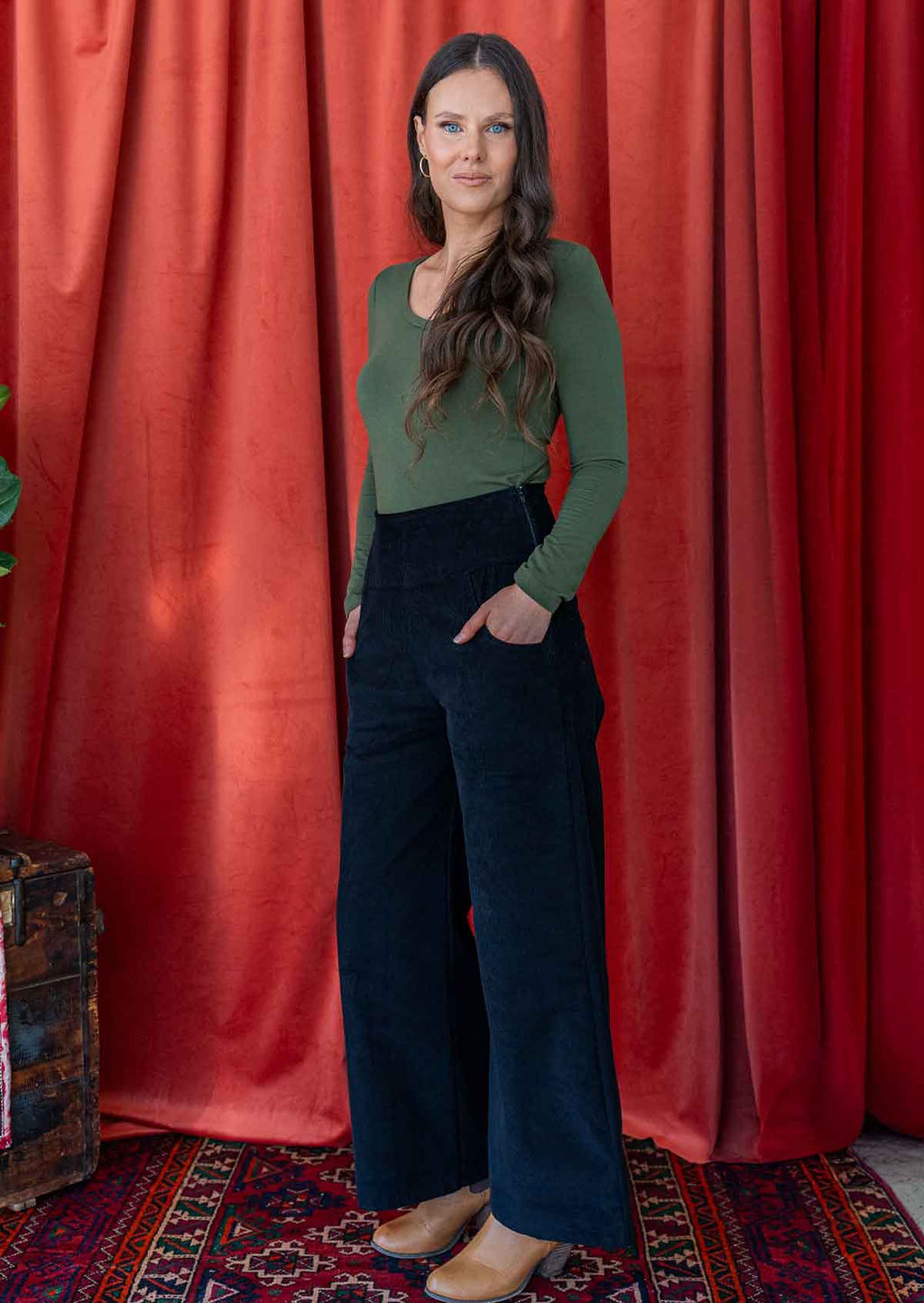 woman wearing long sleeve stretch rayon jersey top in green with v-neck with black corduroy pants 