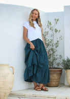 Model wearing a 100% cotton skirt in plain deep teal colour paired with a white top