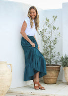 Model wearing a plain deep teal cotton skirt with elasticated and drawstring waistband.