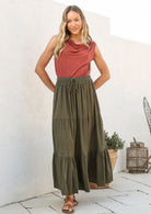 Woman wearing a pink top and olive green skirt with elasticated waistband standing outdoors