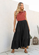 Woman wearing a black cotton maxi skirt with a shoestring tie, paired with a dusty pink sleeveless top