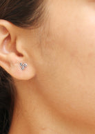 Close-up of an ear wearing a small silver triskele studs with three spirals radiating from the center