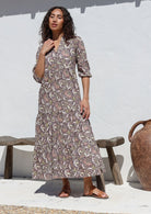 Woman wearing relaxed fit floral printed cotton maxi dress in grey with 3/4 sleeves, pockets and three tiered skirt