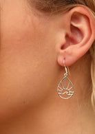 Model wearing silver earrings that are teardrop shape with a sun and wave within it