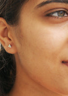 Woman with green eye wearing small sterling silver studs in elongated heart shape
