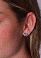 A close-up image of a person wearing sterling silver origami fox stud earrings.