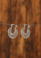Sterling silver flat disc earrings with fine spiral details in a radiating mandala pattern and a hinged clasp