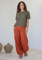 Woman wears wide waistbanded cotton harem pants with a olive green short sleeve top 
