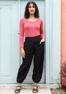 Models poses in black cotton wide leg pants with elasticated ankle, with hand in pocket