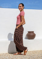 Side pose of model wearing 100% cotton harem pants with wide flat front waistband  elasticated ankles and pockets.