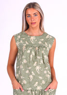 Woman wears pale green cotton sleeveless top with small gathers across the bust