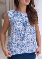 Woman wearing a white based blue floral cotton top with a blurred background.