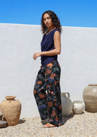 Model poses in black floral cotton pants with side zipper, pockets and wide leg fit