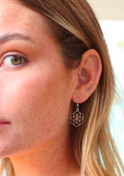 Woman wears silver hook earrings with sacred geometry of seven intersecting circles