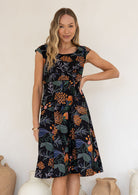 Model in knee length, black 100 percent cotton scoop neck retro style dress with pockets and cap sleeves 
