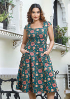 Model in retro style, knee length cotton dress with scoop neck, cap sleeves and hands in pocket.