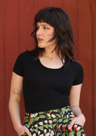 Woman with dark hair wearing a black stretch rayon t-shirt.