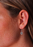 Close up of sterling silver hook earring featuring a small circle with 3 'V's inside it.