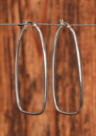 92.5%  stretched silver hoop earrings sitting on a wire for display
