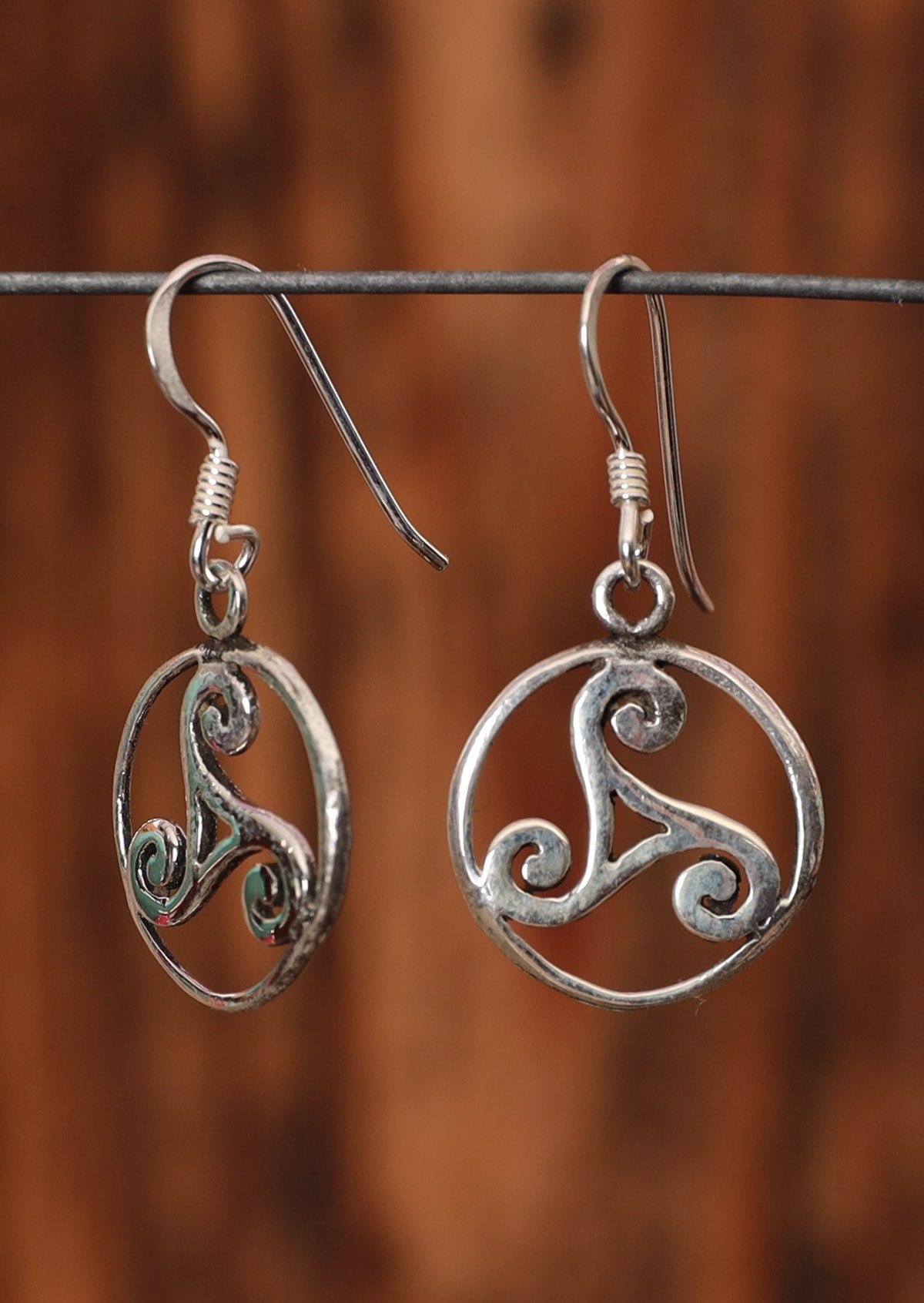 92.5% silver Triskele earrings in a circle hanging on a wire for display.