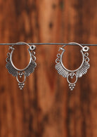 92.5% silver circular ornate earrings hanging on a wire for display.