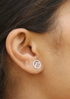 Woman wears sterling silver circular Alps studs featuring intricate cutout details