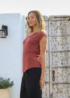 Woman wearing a 100% rayon terracotta V-neck top and black cotton pants standing outdoors.