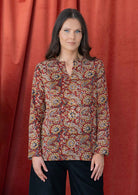 Model wears cotton long sleeve top with keyhole cutout and round neckline in a rusty indian floral print.
