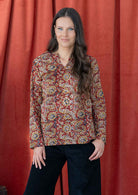 Model wears lightweight, cotton long sleeve top with keyhole cutout, in a earthy red based floral print.