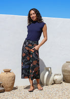 Woman wearing a navy basic rayon top and black botanical print wide leg 3/4 cotton pants with side zipper and pockets