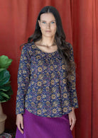 Woman wearing 100% cotton long sleeve top with tiny pleated details across the bodice and round neck.