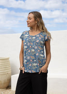 Woman wearing a blue cotton top with pink, lemon yellow and green floral print