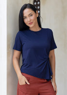 Woman wearing a navy blue short sleeve rayon top and rust pants with hand in pocket