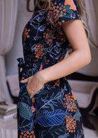 100 percent cotton short sleeved dress with pockets and a fabric waist tie in black based retro botanical print.