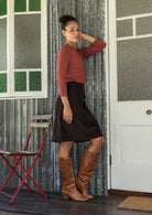 Woman stands sideways wearing a  cotton corduroy skirt and basic top 