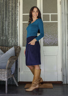 Woman stands sideways wearing a  cotton corduroy skirt and basic top with one hand in her pocket