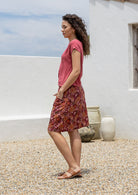 Woman posing in a 100% cotton floral skirt in black with side zipper, piped detailing at waist and pockets.