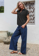 Woman wearing a black relaxed fit cotton top with a collar, paired with long blue pants