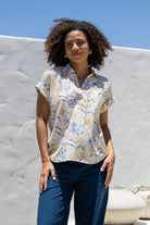 Woman poses in relaxed fit cotton short sleeve top with rolled cuffs sleeves, collar and V neckline.