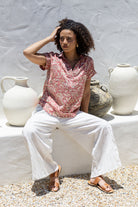 Woman sitting outdoors wearing 100% cotton top with white pants 