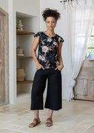 Woman standing in a 100 percent cotton floral print top with cap sleeves, round neckline and keyhole cutout.